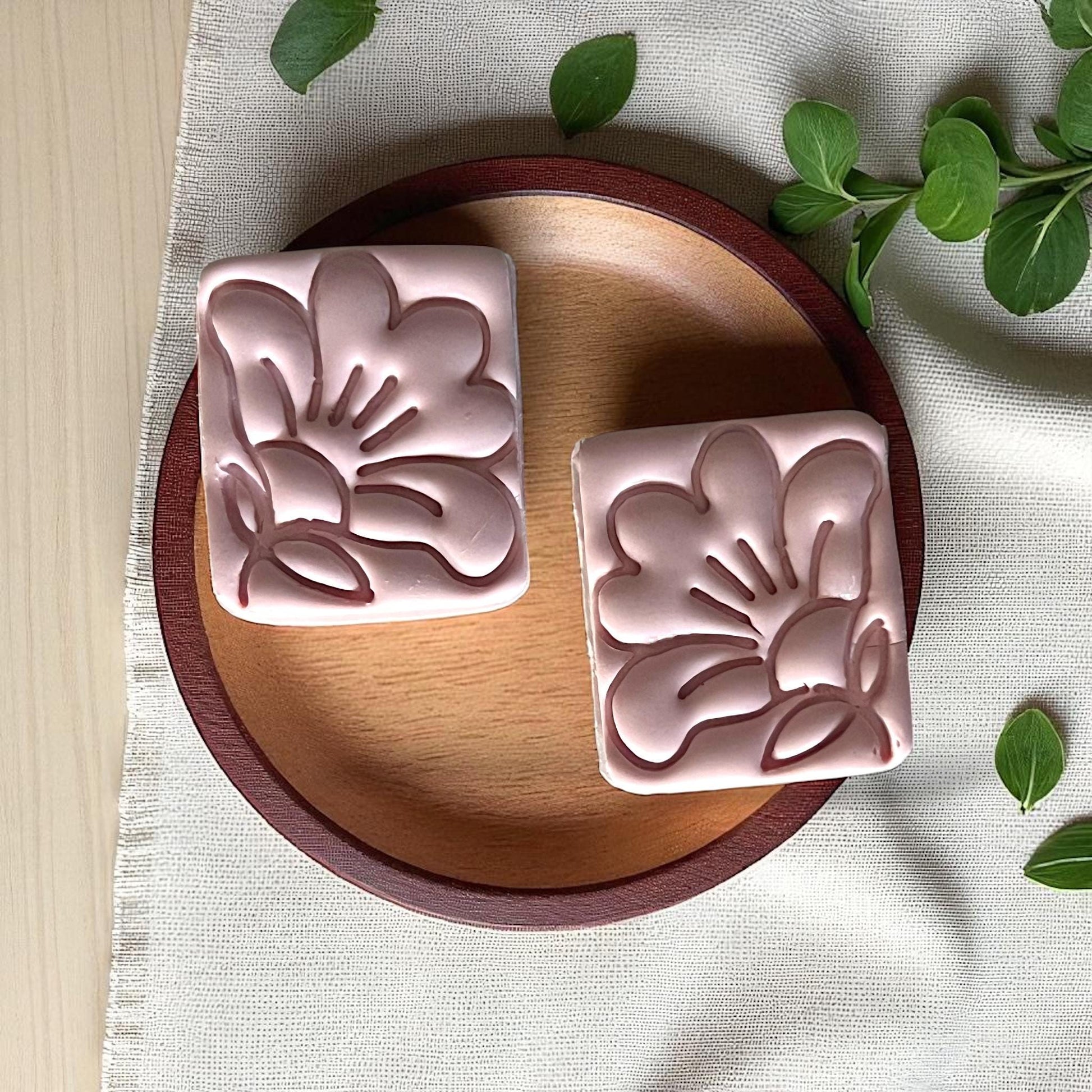 Closeup of square floral clay imprints with hibiscus design on wood plate