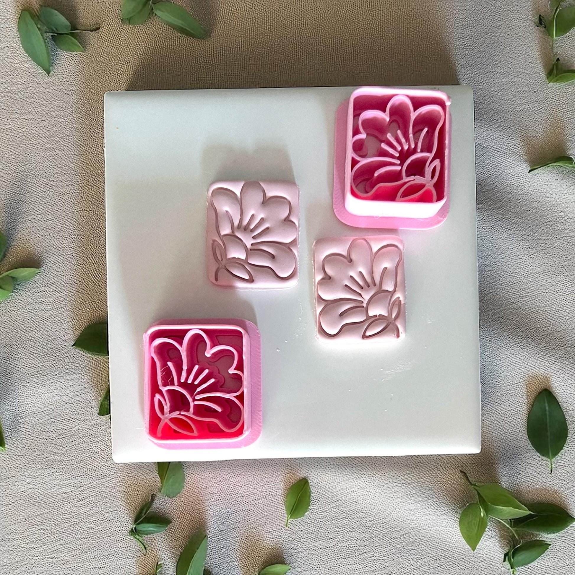 Square hibiscus clay cutters with clay imprints on white tile