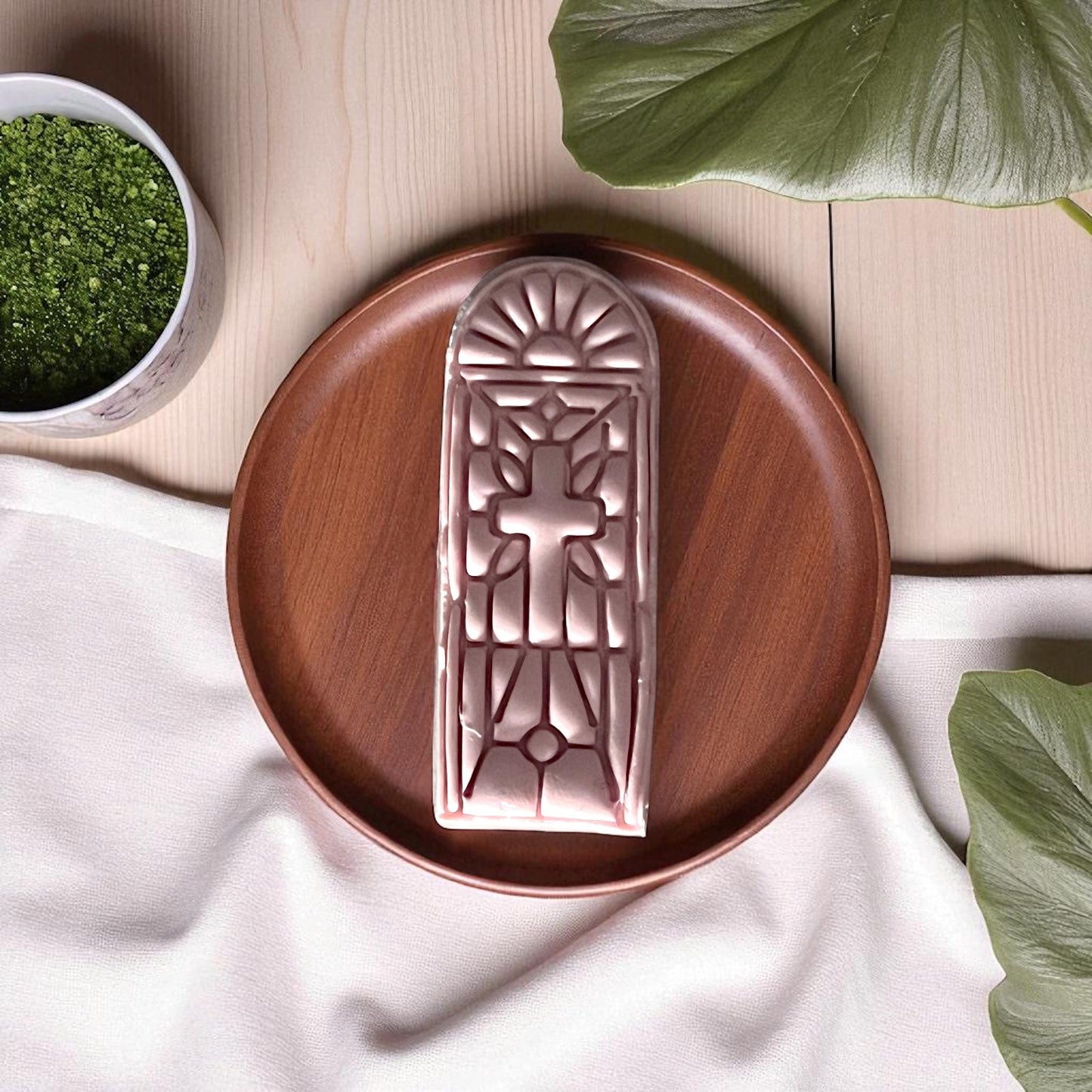 Clay imprint of stained glass window cross design on wood plate