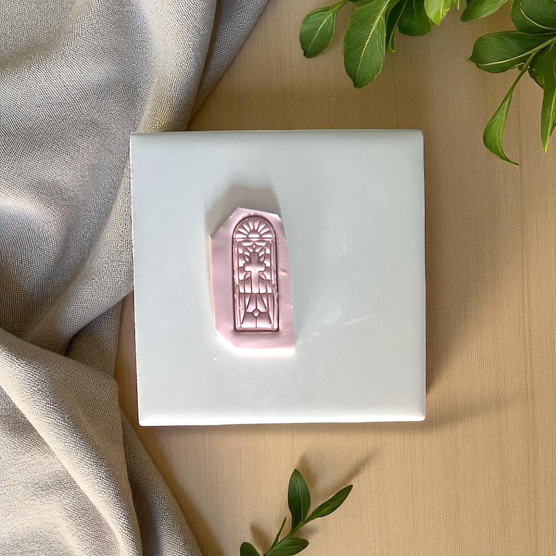 Polymer clay imprint of stained glass cross design on white tile