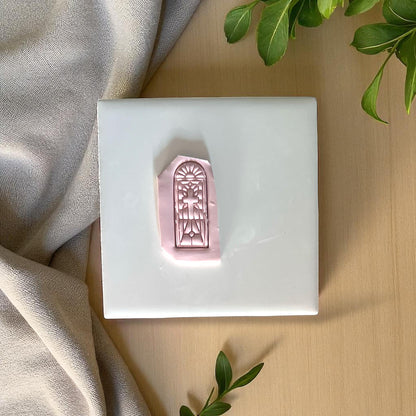 Polymer clay imprint of stained glass cross design on white tile