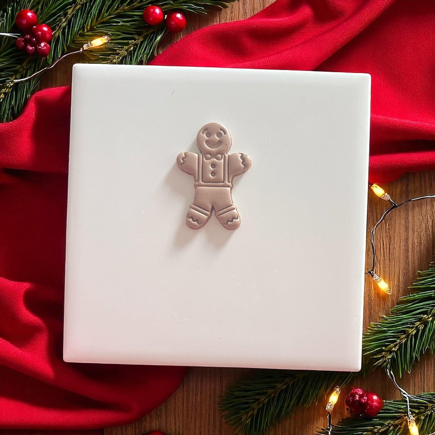Gingerbread man clay imprint on white tile with red cloth
