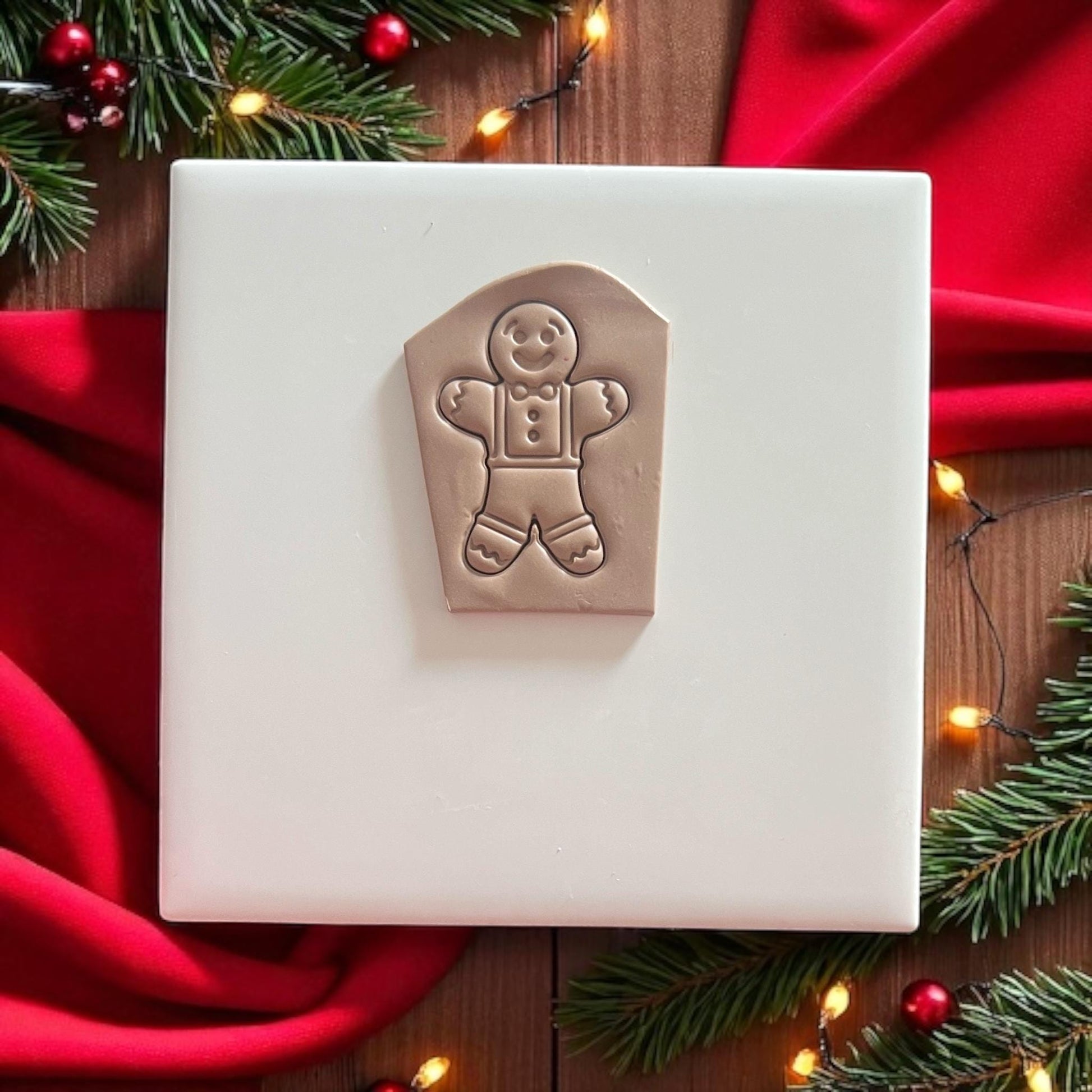 Polymer clay imprint of gingerbread man with festive background