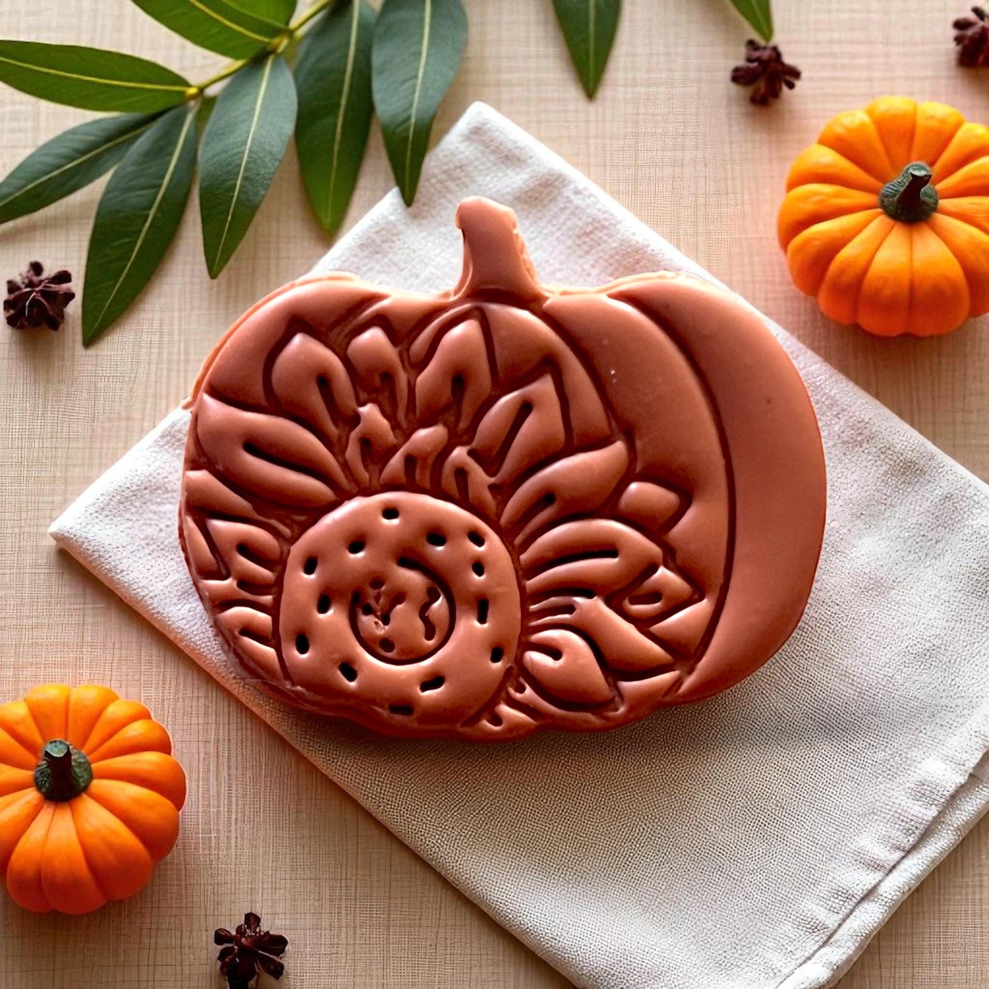 Clay impression of sunflower pumpkin cutter on napkin with mini pumpkins