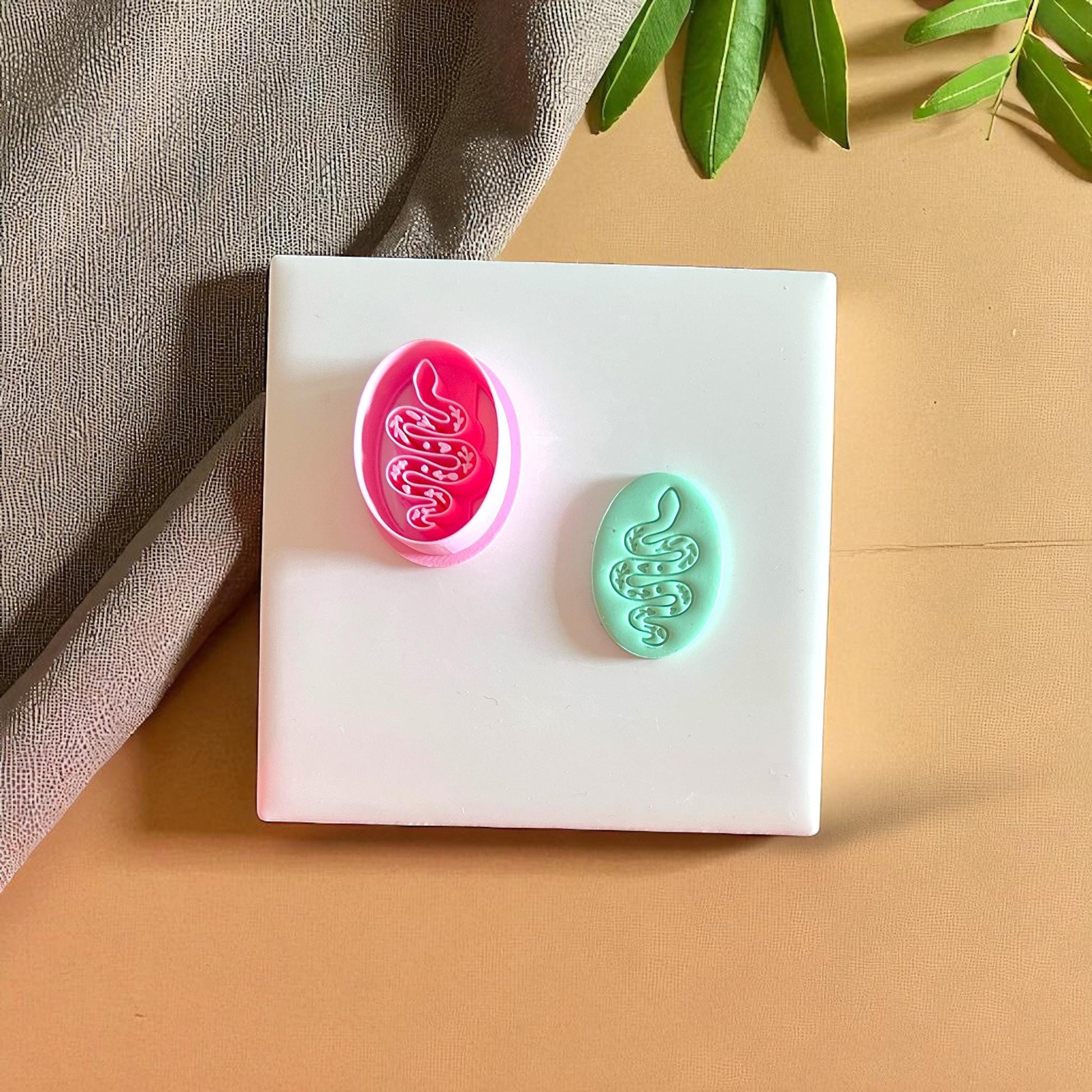 Pink snake clay cutter with teal clay snake design
