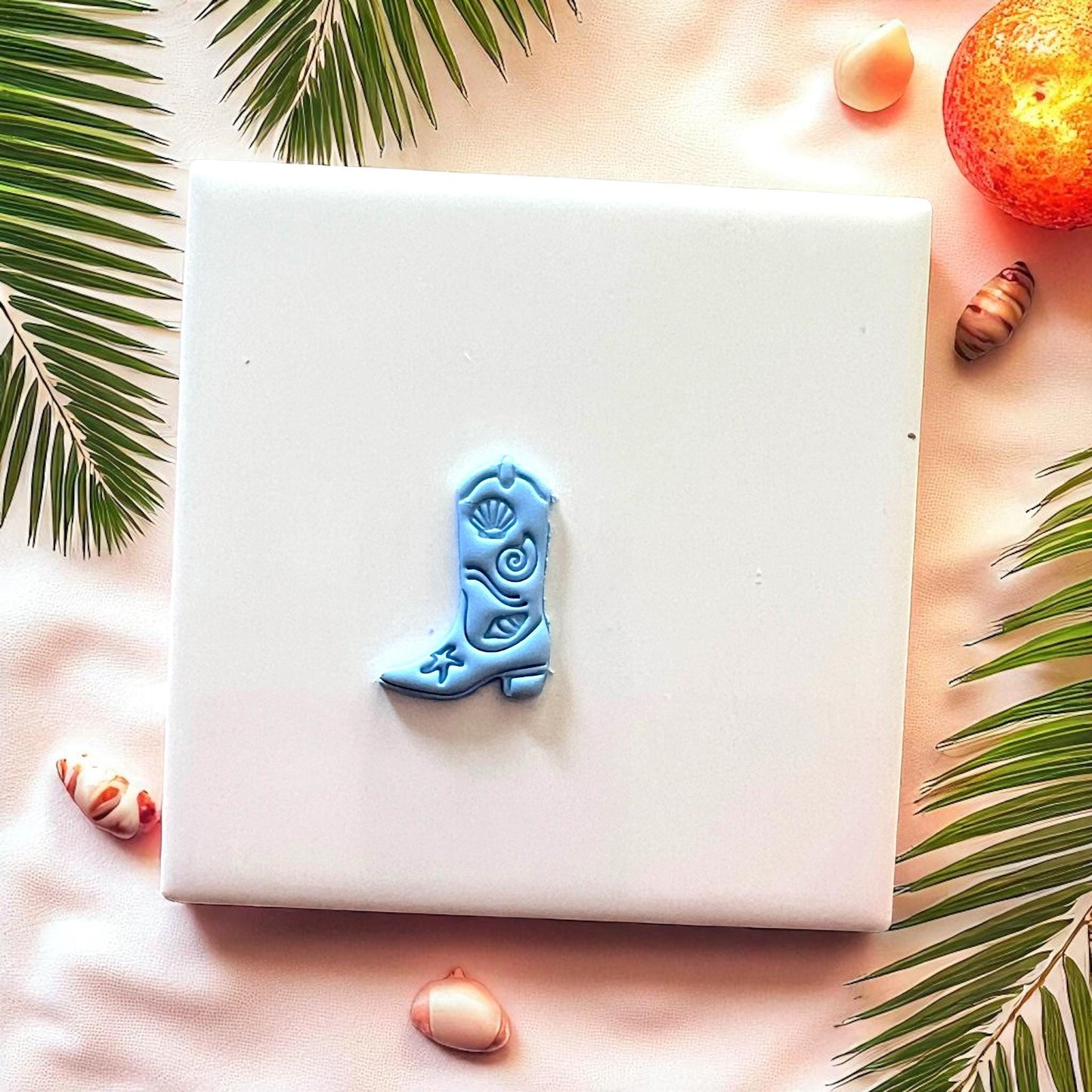 Small blue cowboy boot clay design on white tile