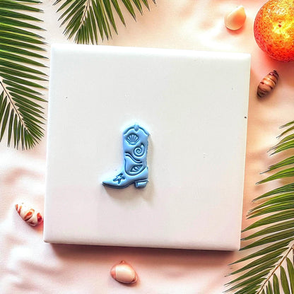 Small blue cowboy boot clay design on white tile