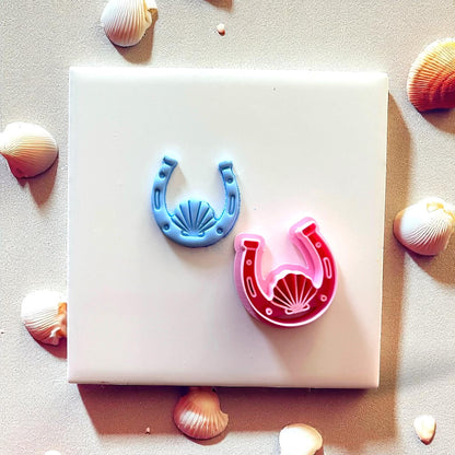 Blue clay horseshoe with seashell next to red cutter
