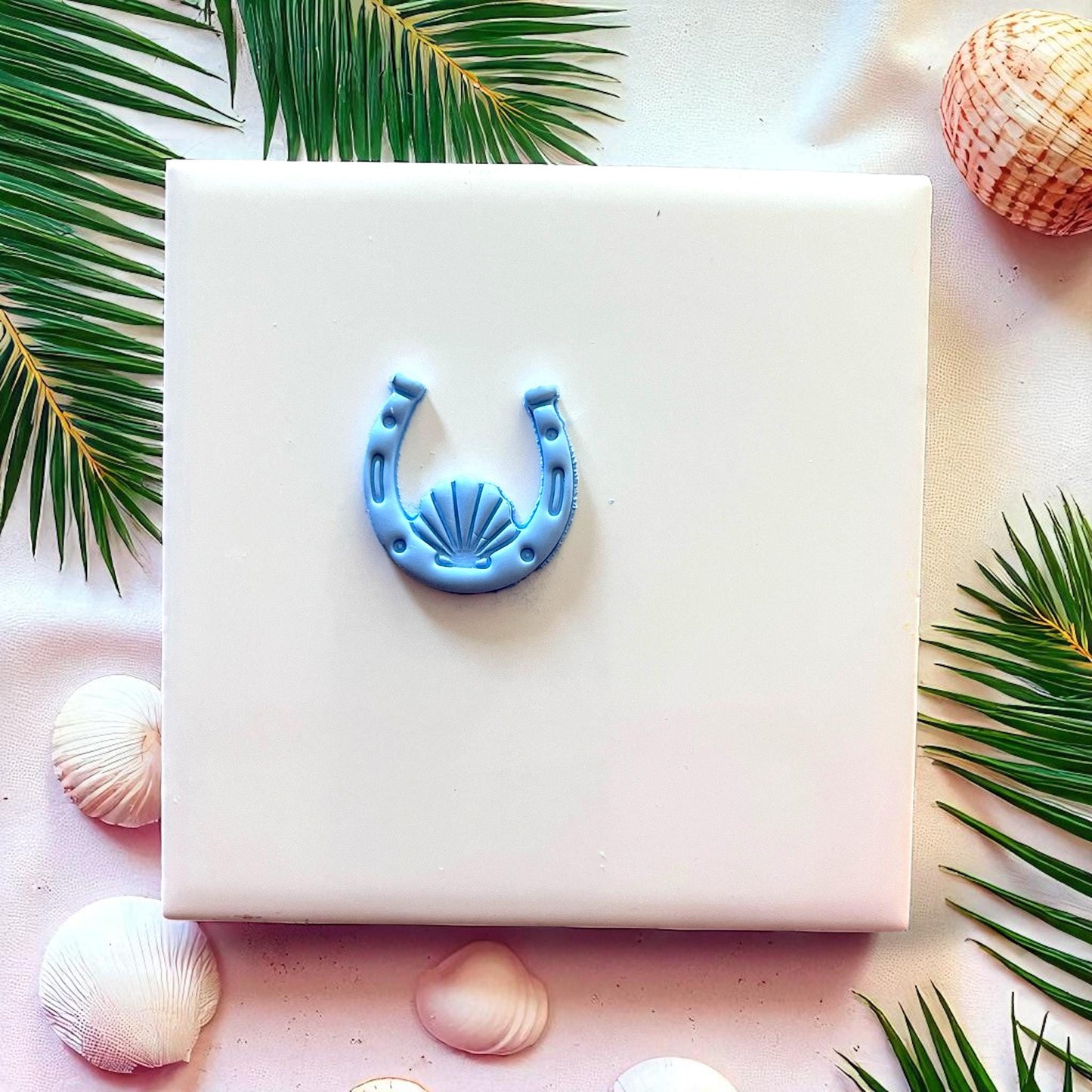 Blue clay horseshoe seashell design on white tile with seashell decor