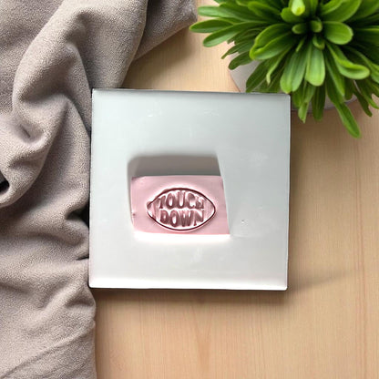 Small pink touchdown football clay imprint on white tile