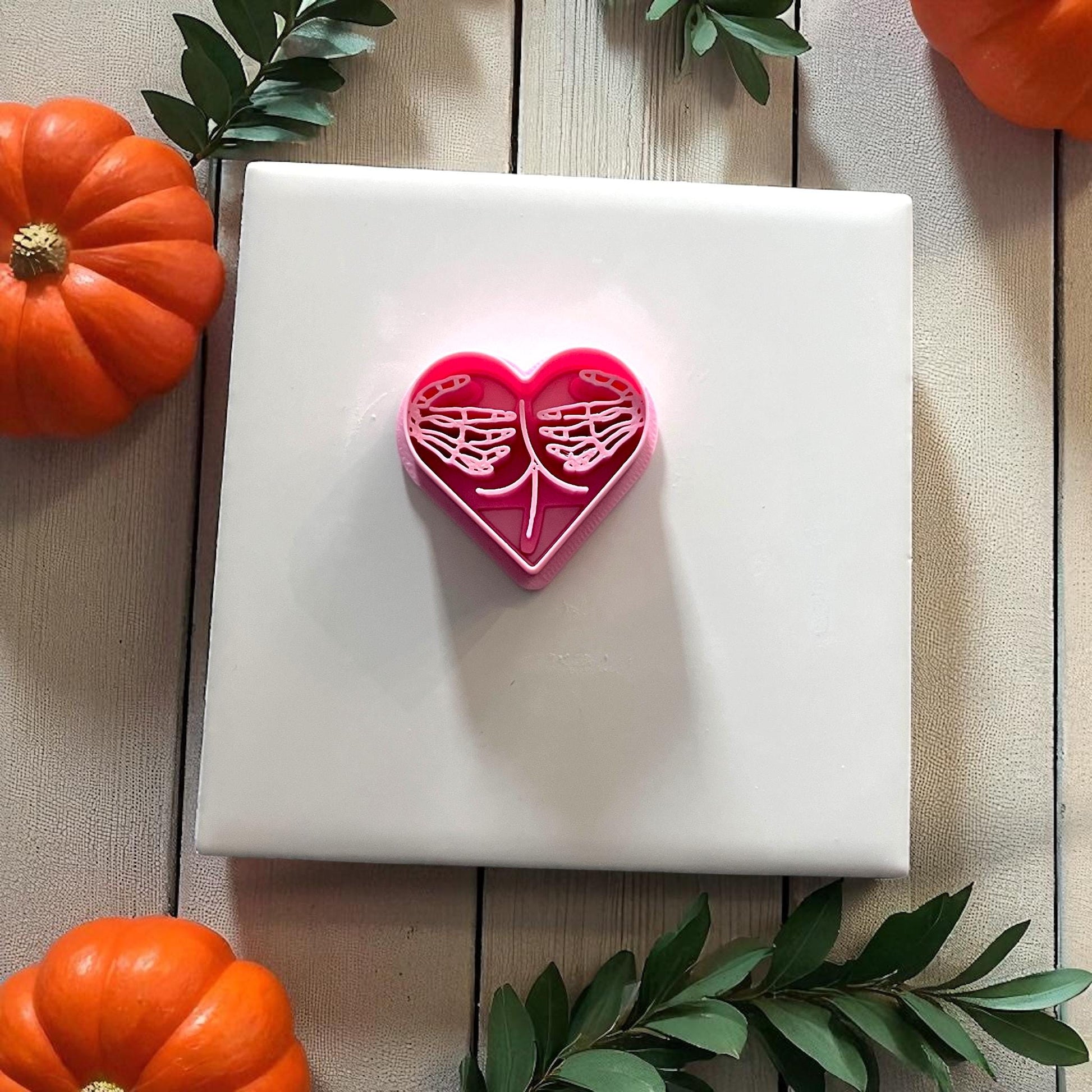 Pink skeleton hands heart clay cutter on white tile