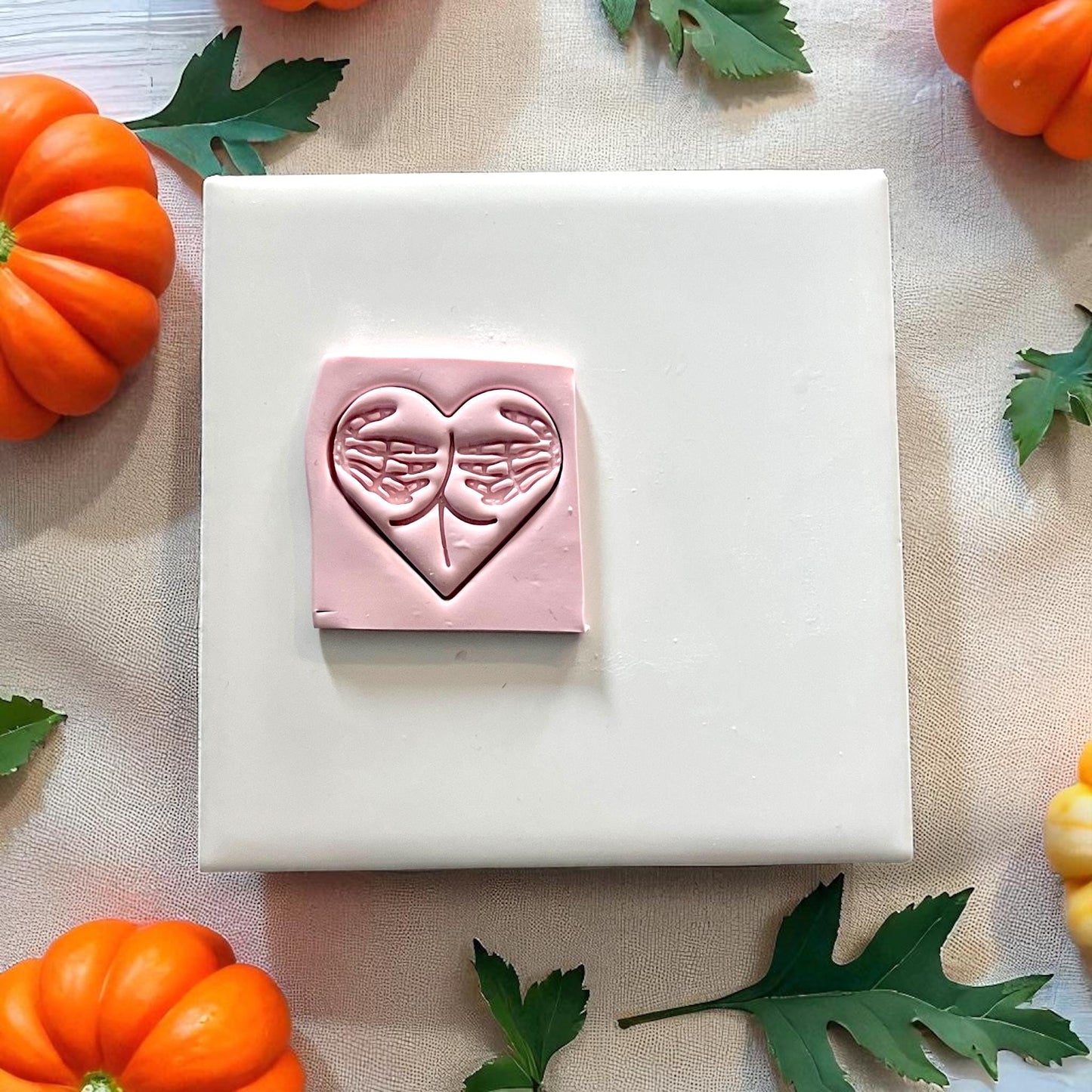 Pink clay impression of skeleton hands forming heart