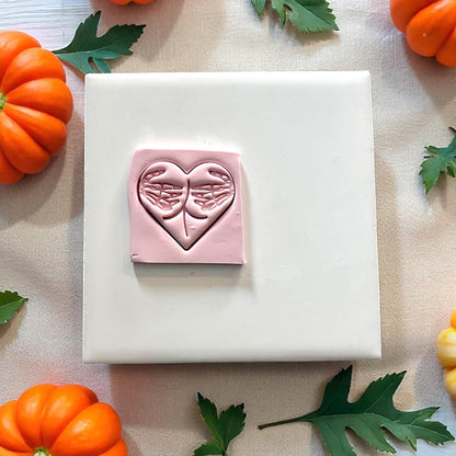 Pink clay impression of skeleton hands forming heart