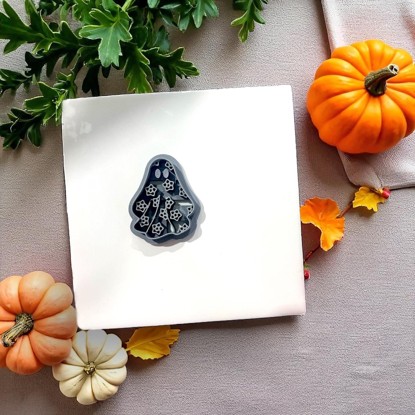 Black floral ghost cutter on white tile with pumpkins