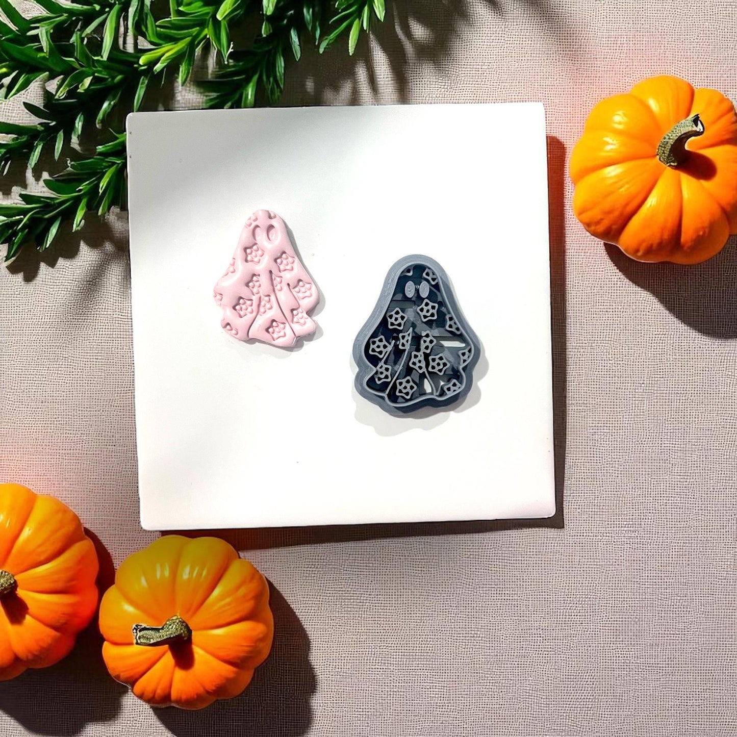Pink floral ghost clay piece beside black cutter with pumpkins