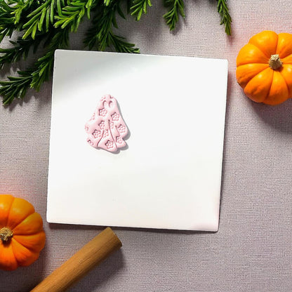Small pink floral ghost clay piece on white tile with pumpkins