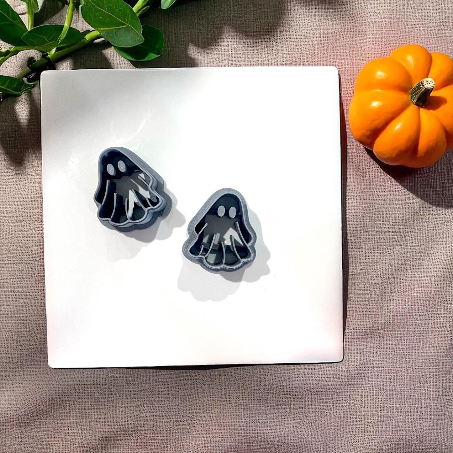 Two black ghost cutters on white tile with pumpkin