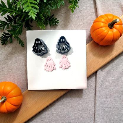 Black ghost cutters with pink clay ghosts beside pumpkins