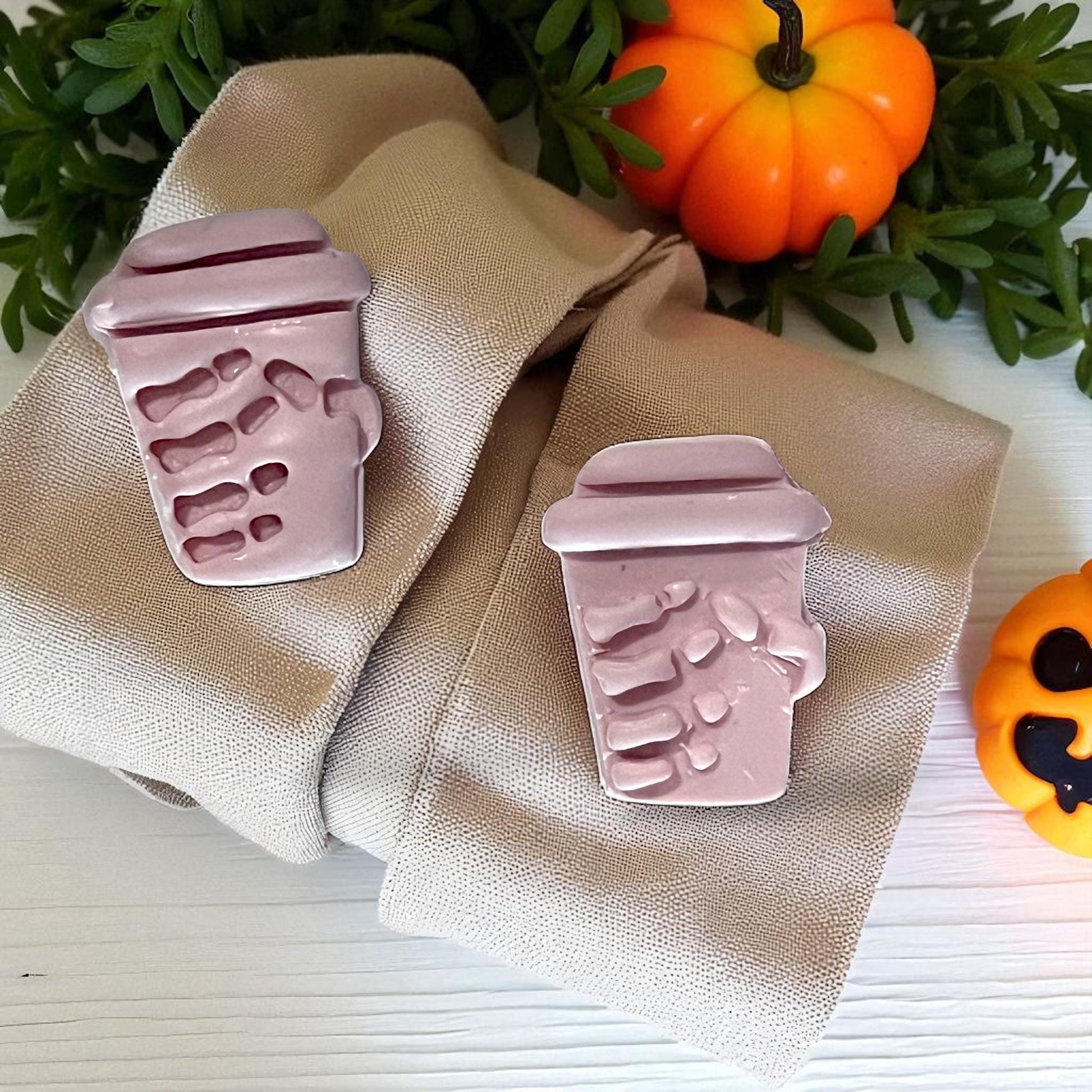 Pink clay skeleton hand coffee cups on napkin with pumpkins