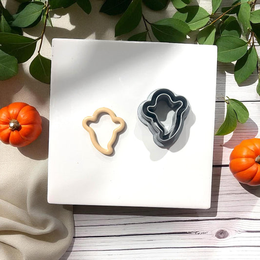 Thin ghost clay cutter and beige clay ghost side by side with greenery