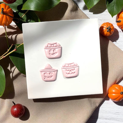 Three pink pumpkin bucket faces on white background