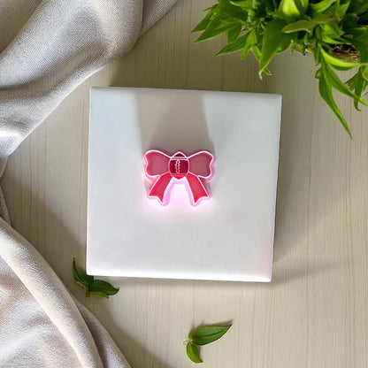 Pink football bow clay cutter on white tile