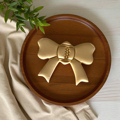 Large gold clay football bow on wooden plate with greenery