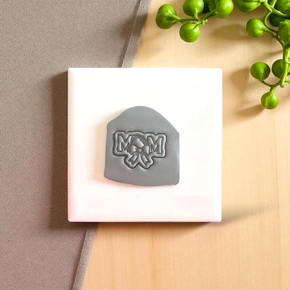 Gray football mom clay imprint with bow design on white tile