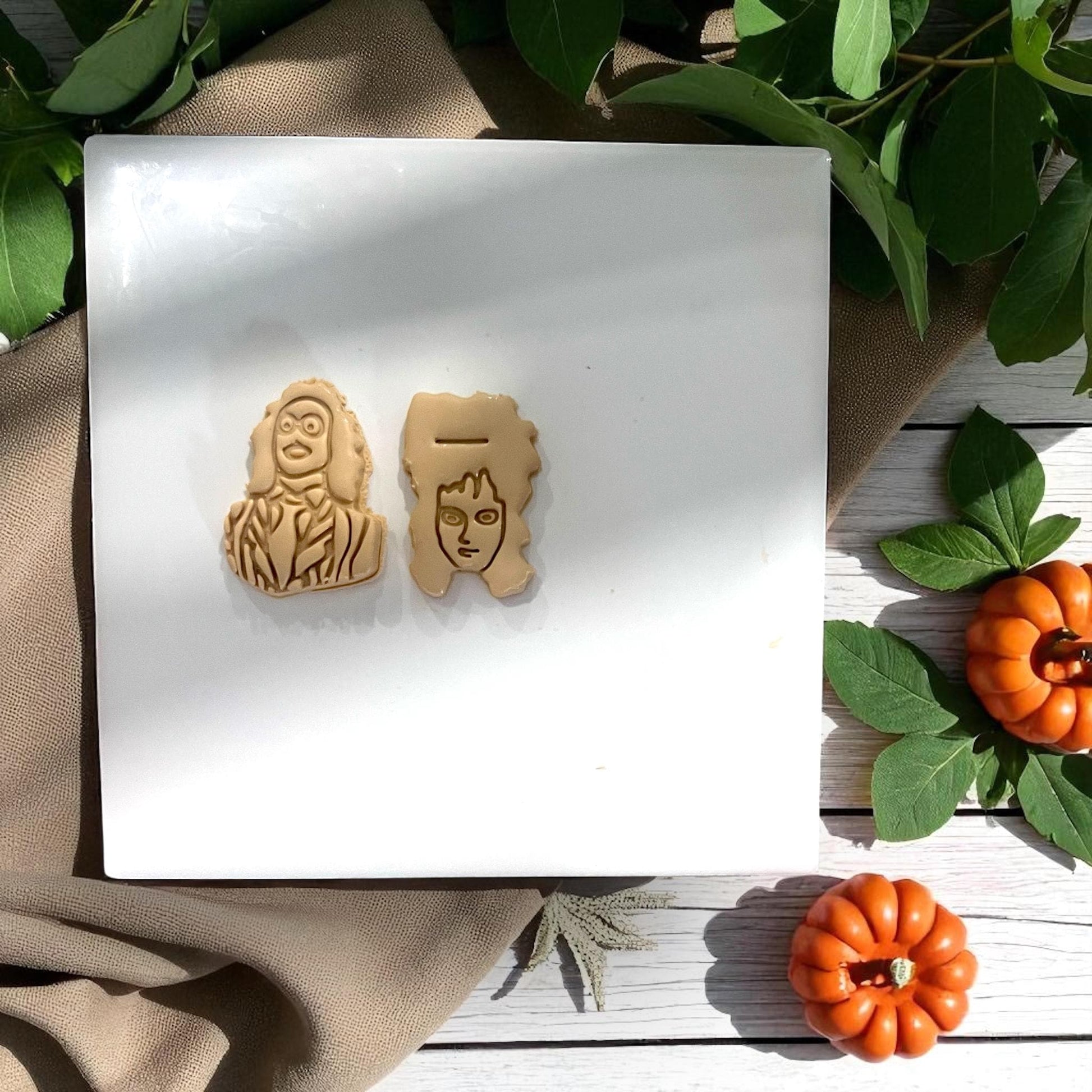 Beetlejuice and Lydia clay impressions side by side on white tile with pumpkins