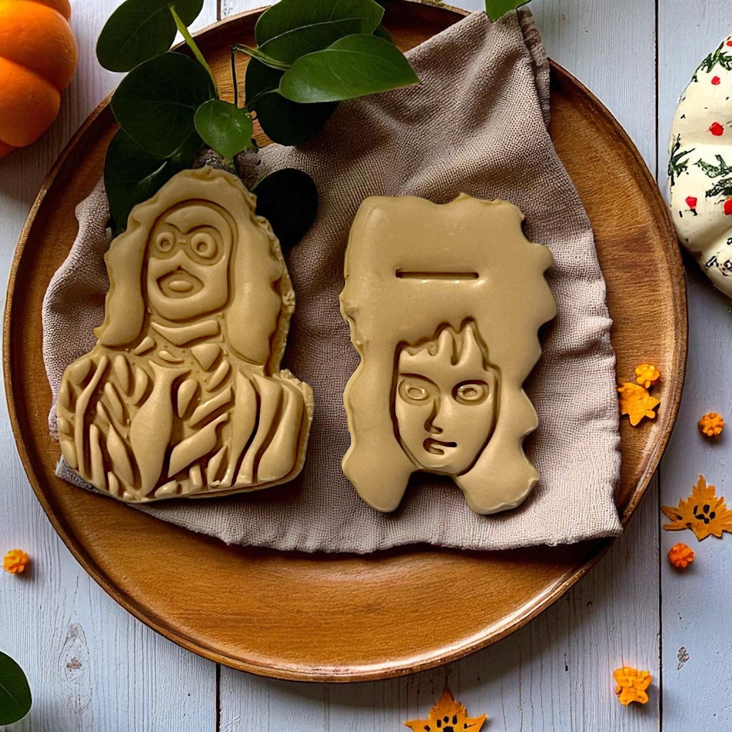 Large Beetlejuice and Lydia clay designs on wooden plate with greenery