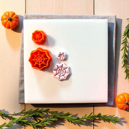 Spiderweb and spider clay cutters with clay impressions on white tile