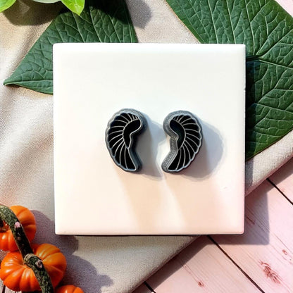 Black scarab wing clay cutters on white tile with greenery and pumpkins