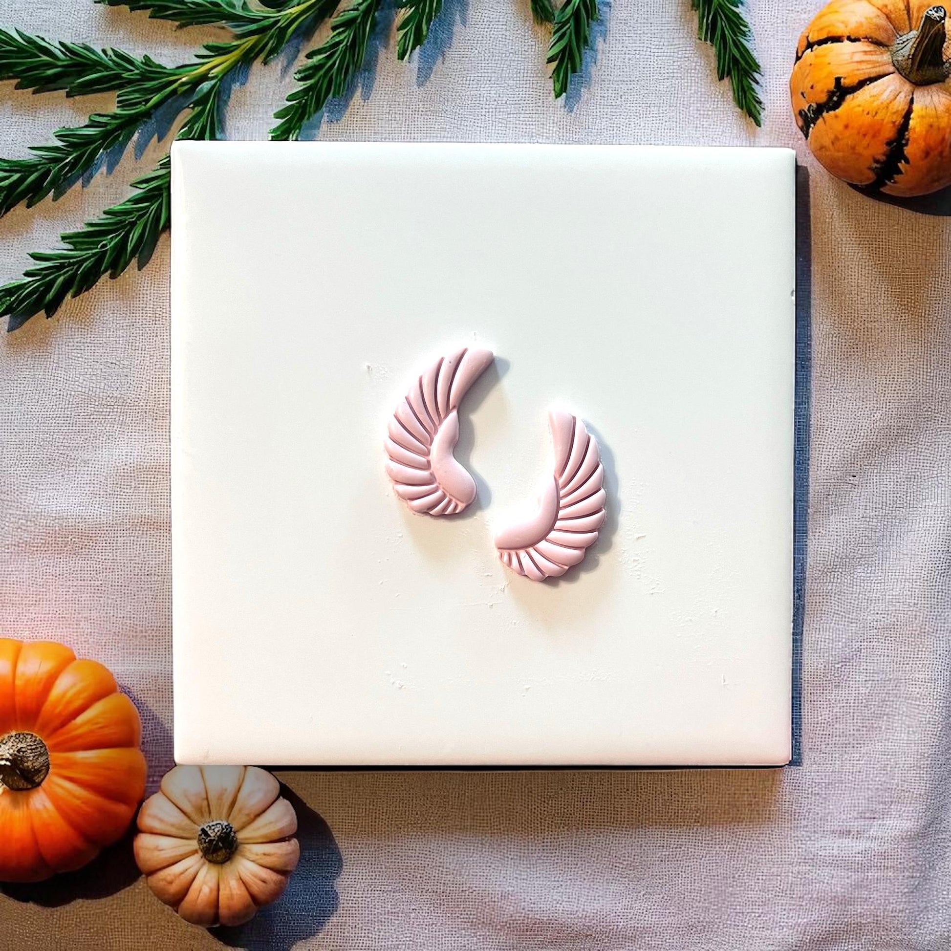 Small pink scarab wing clay impressions on white tile with pumpkins