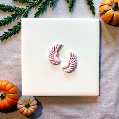 Small pink scarab wing clay impressions on white tile with pumpkins