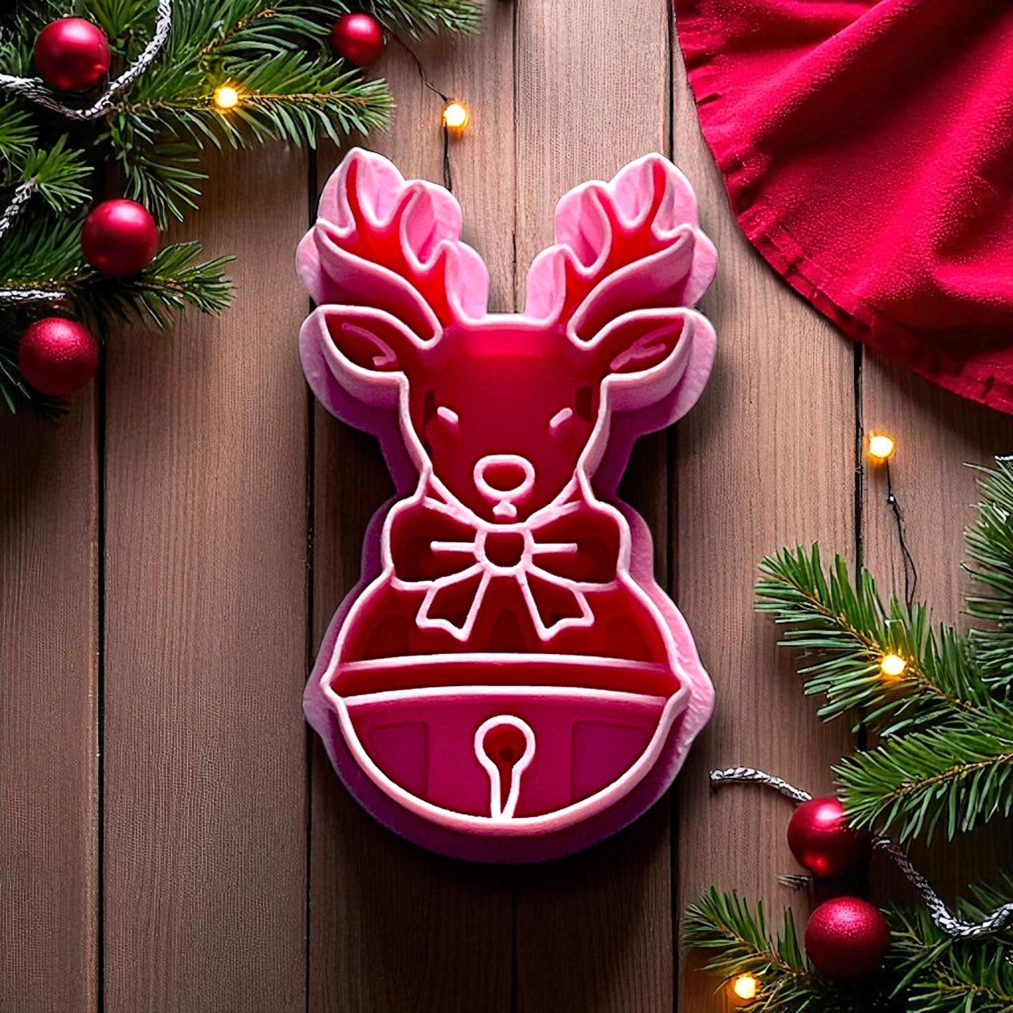 Reindeer clay imprint with antlers, bow, and bell on pink clay slab