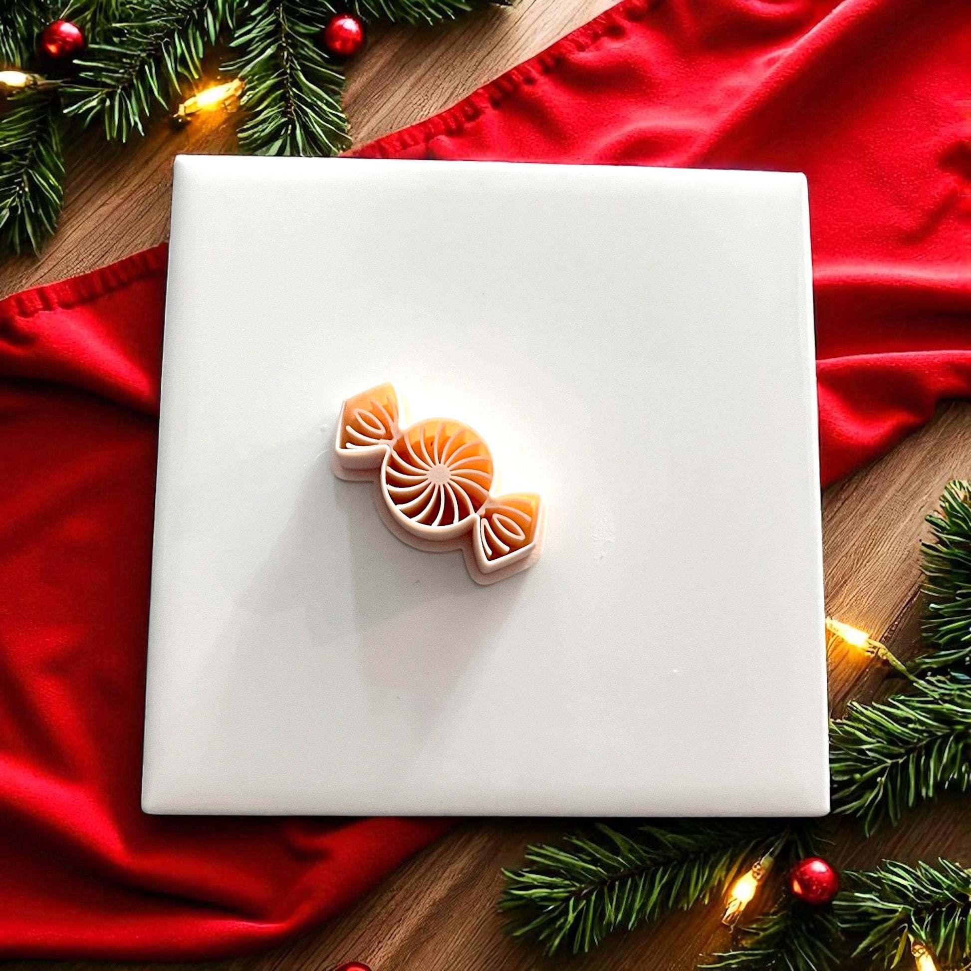 Peppermint candy polymer clay cutter on white tile with red fabric and Christmas greenery