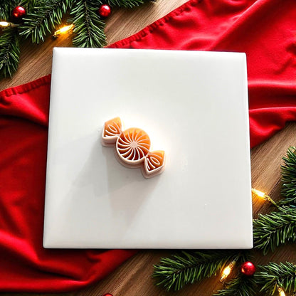 Peppermint candy polymer clay cutter on white tile with red fabric and Christmas greenery