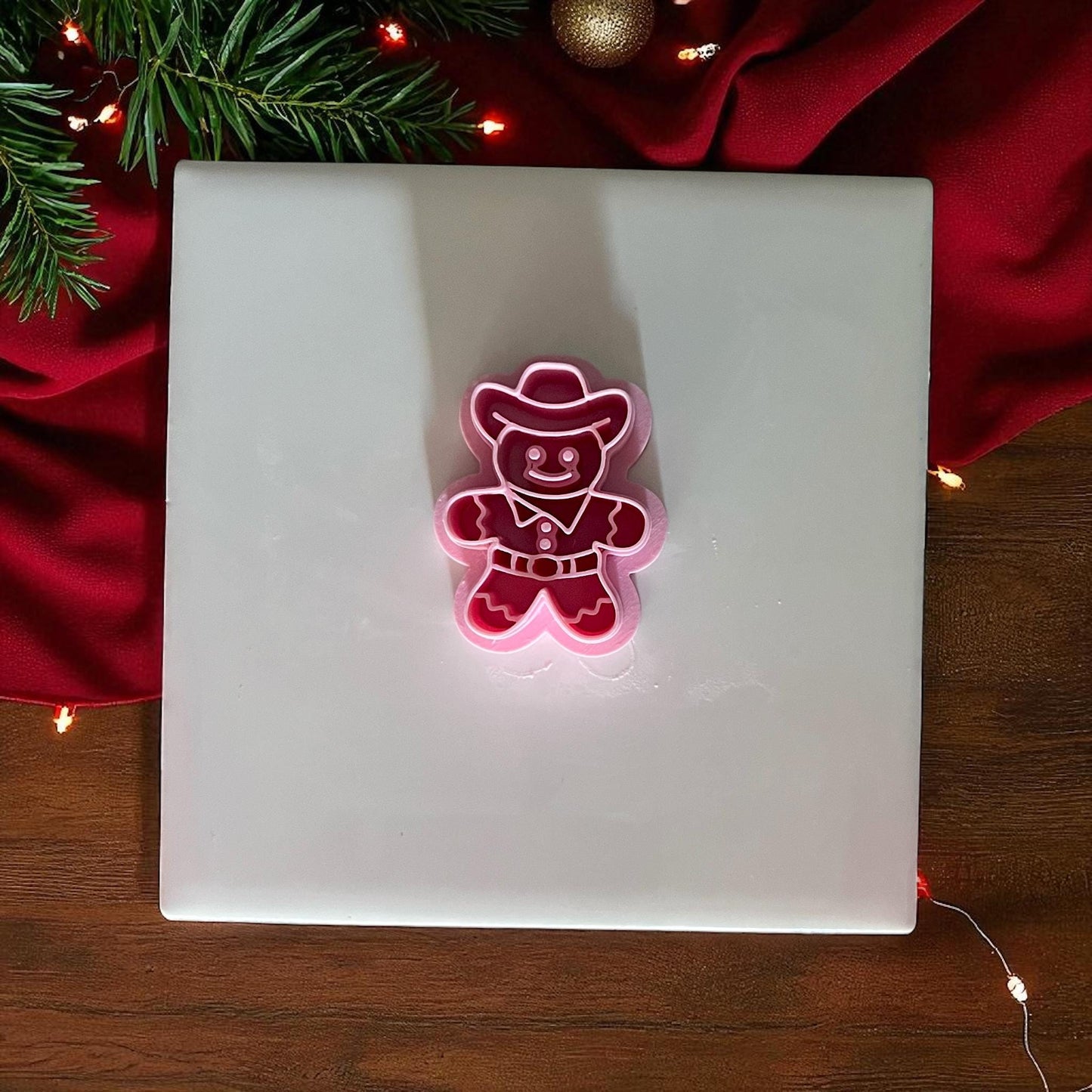 Cowboy gingerbread man clay cutter on white tile with red Christmas fabric