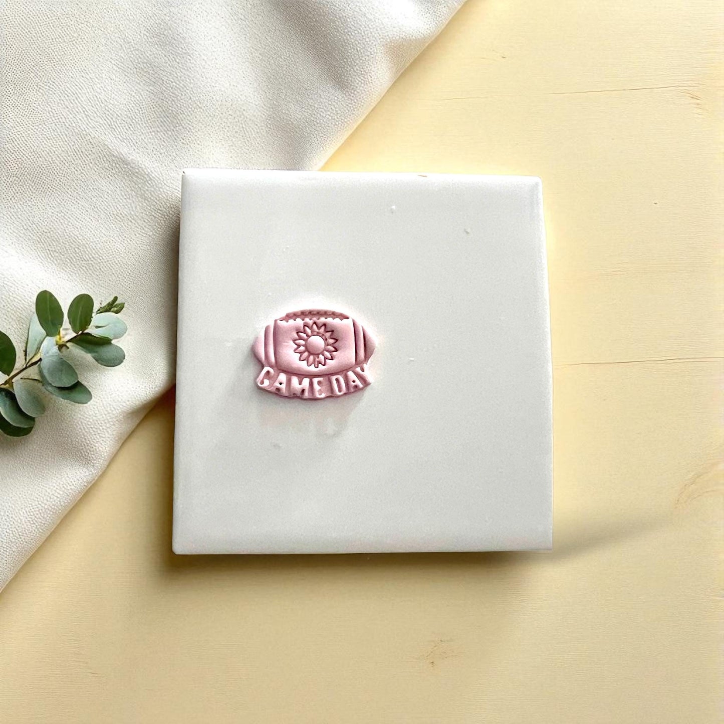 Small sunflower football game day clay imprint on white tile