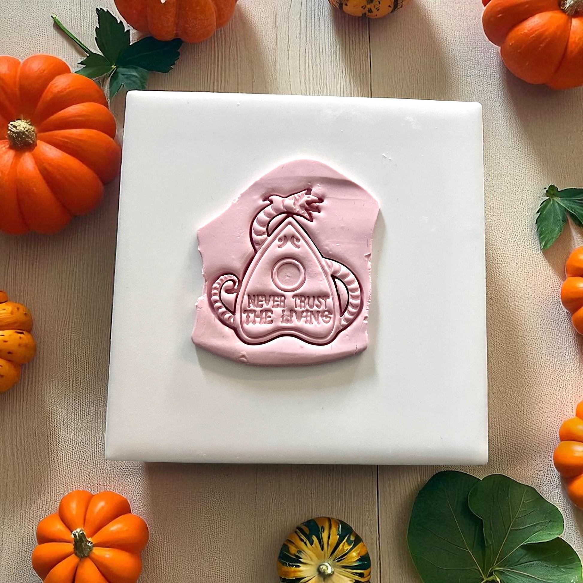 Large clay imprint of planchette cutter with Never Trust the Living design