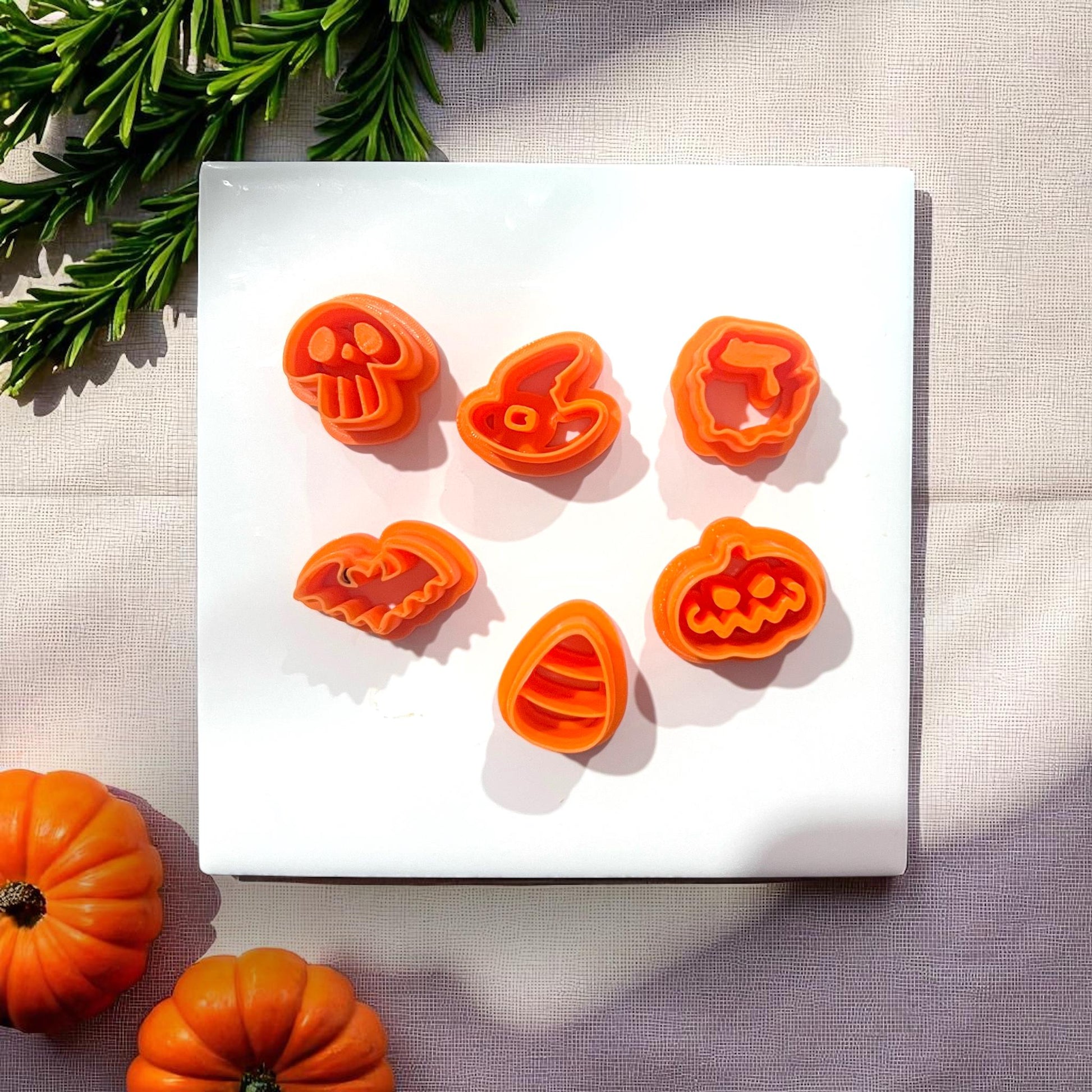 Orange Halloween clay cutters on white tile with pumpkins