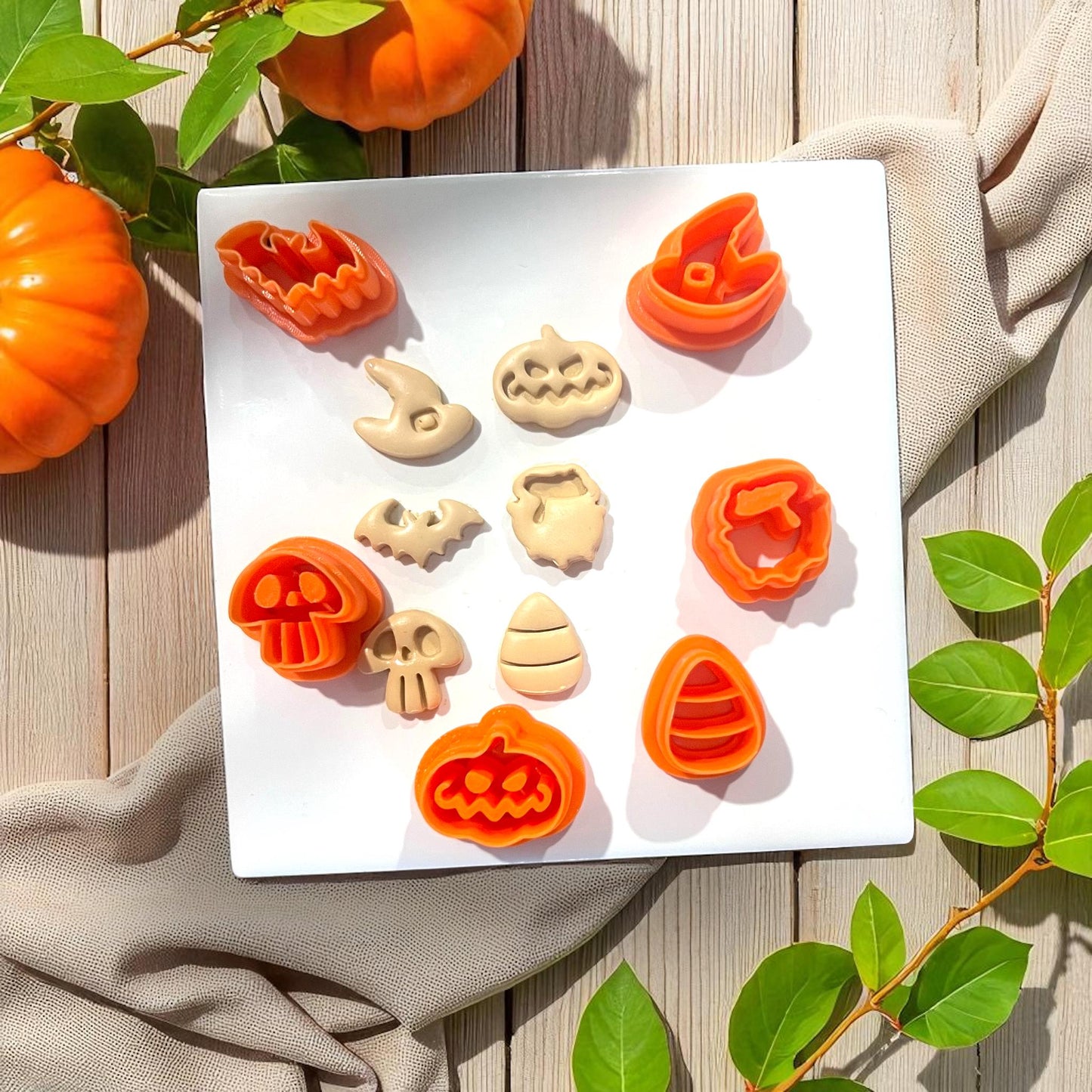 Halloween clay cutters and shapes displayed on white tile with pumpkins