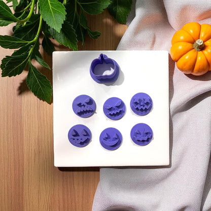 Purple pumpkin face clay cutters on white tile with pumpkins