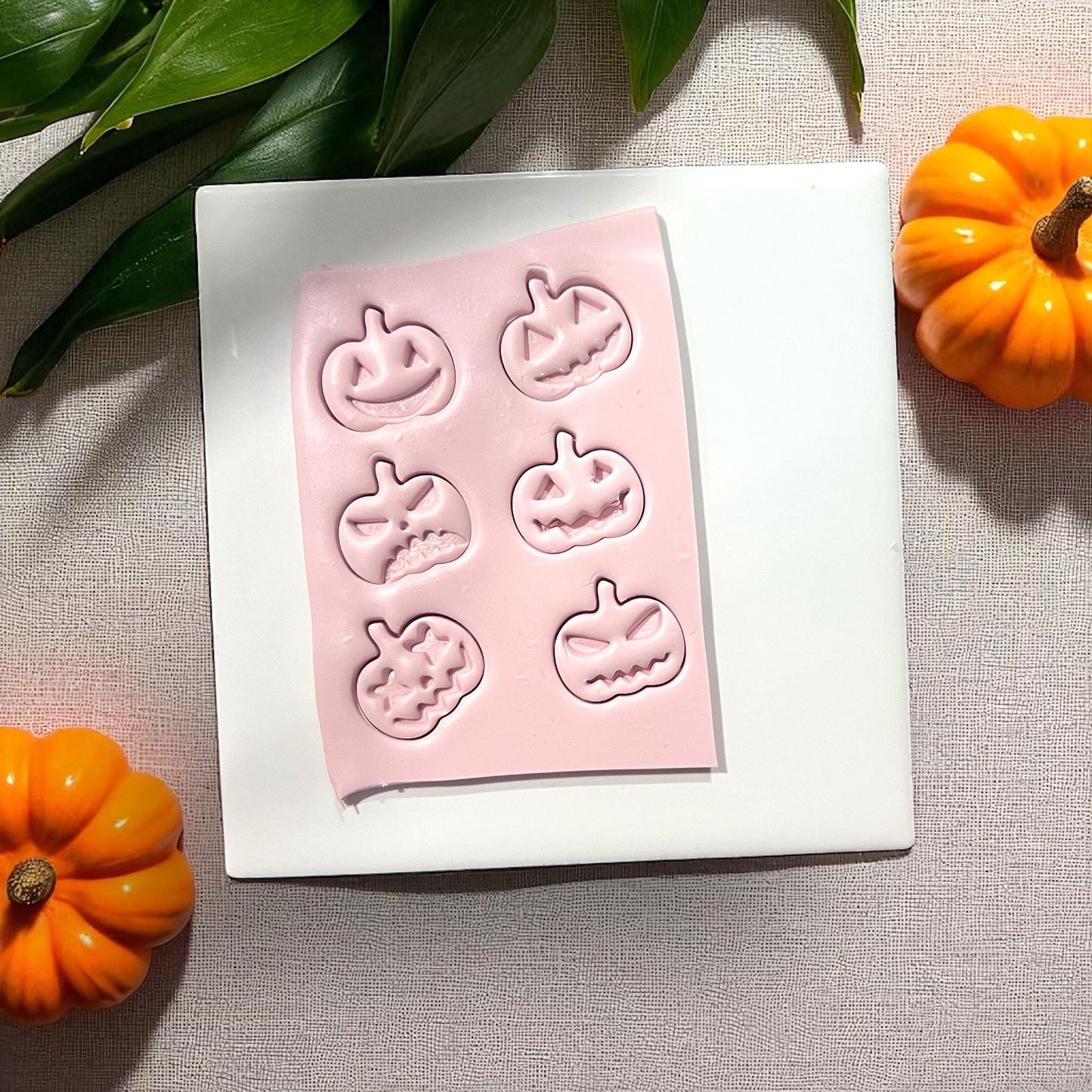 Pink clay slab with pumpkin face impressions on white tile