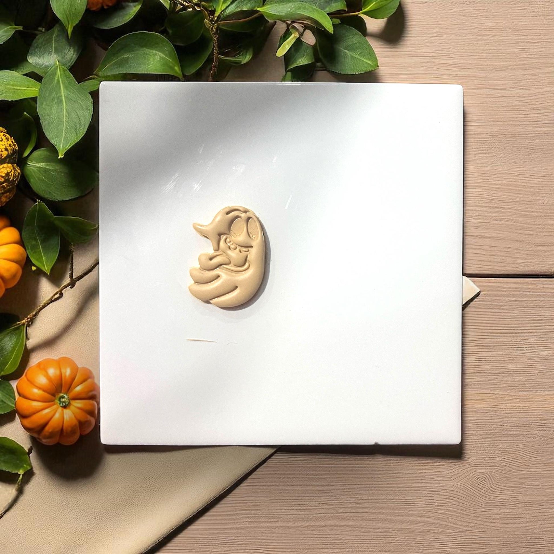 Single silly ghost clay shape with tongue out on white tile