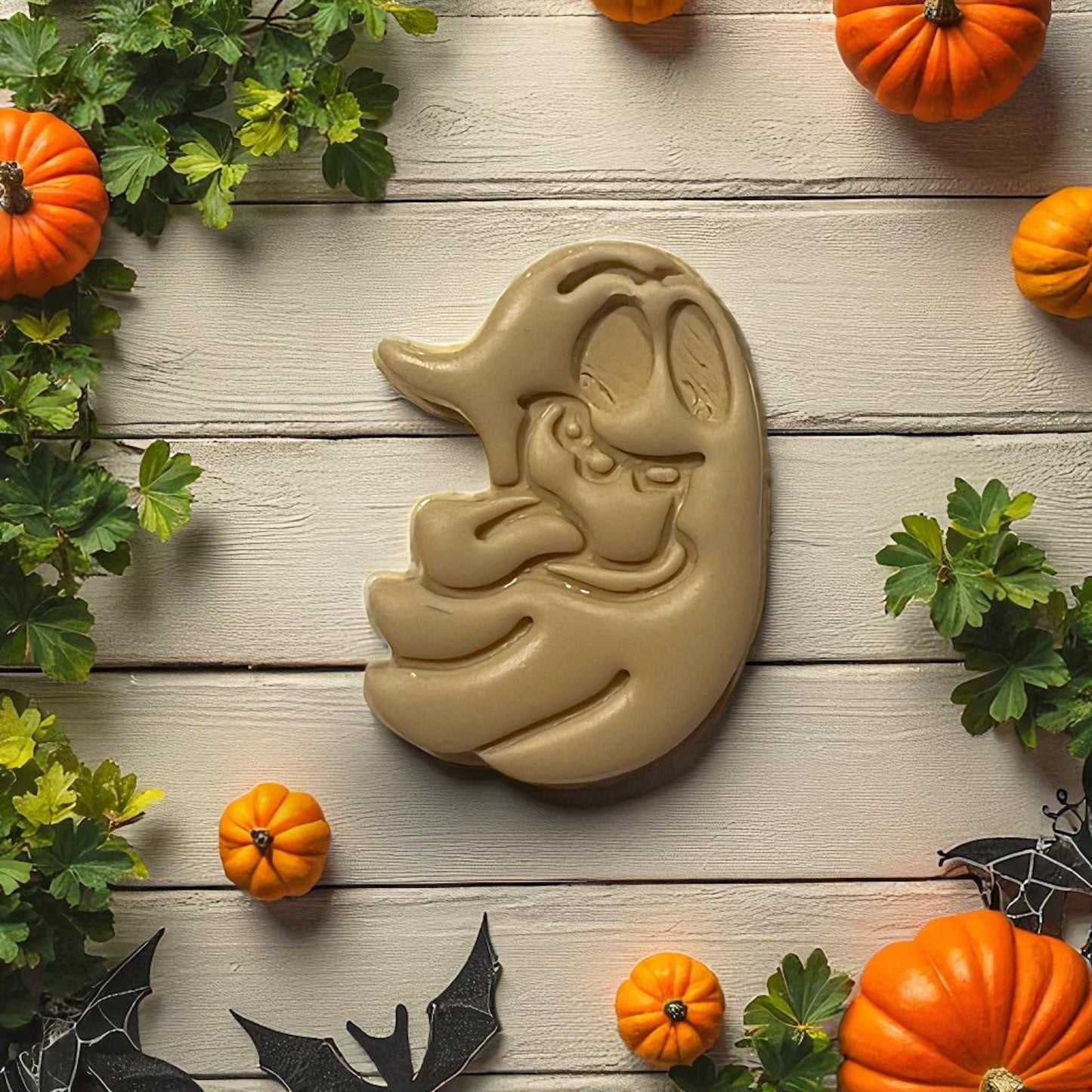 Brown silly ghost clay shape with tongue out surrounded by pumpkins and leaves