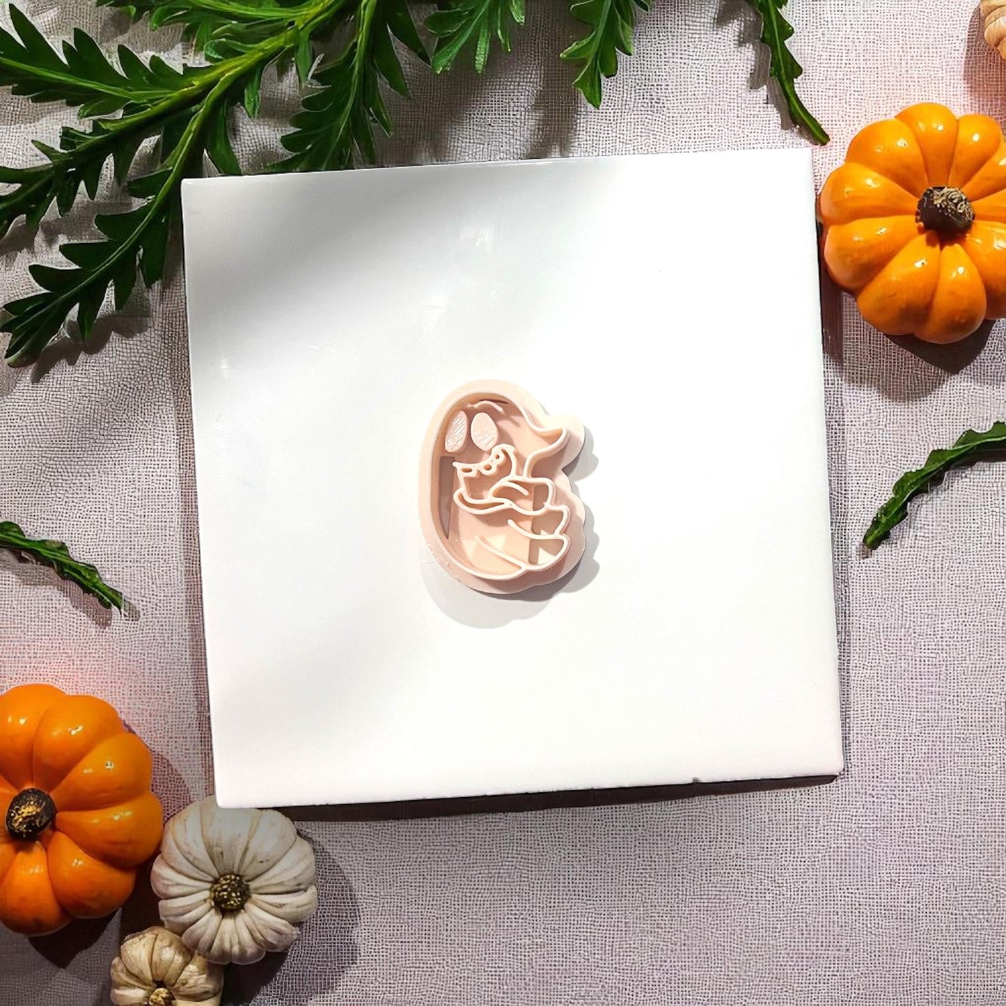 Pink silly ghost clay cutter with tongue sticking out on white tile