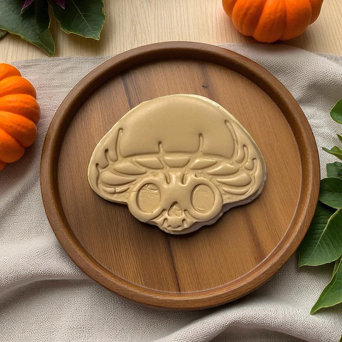 Large mushroom skull clay shape on wooden plate with pumpkins