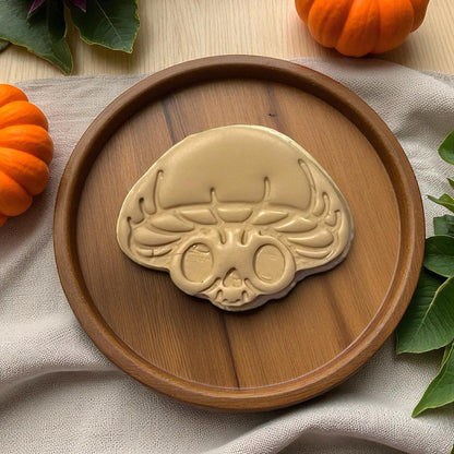 Large mushroom skull clay shape on wooden plate with pumpkins
