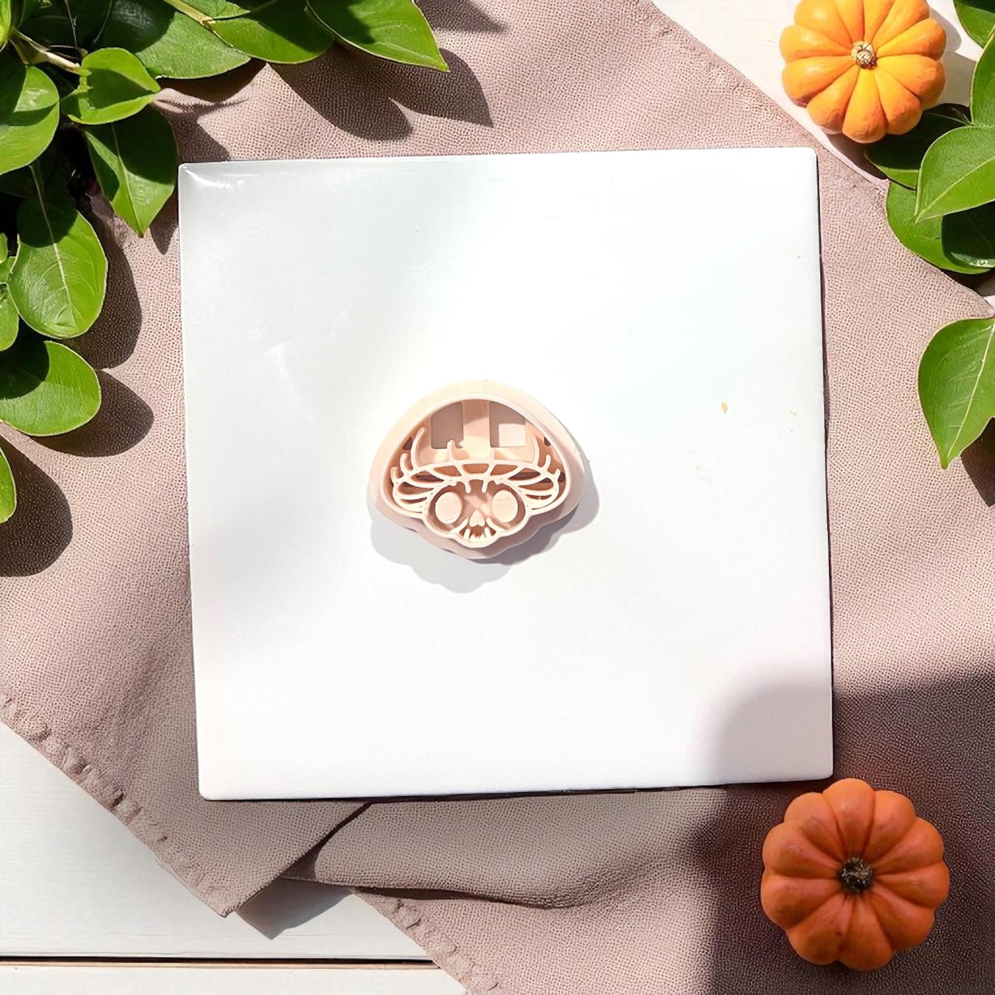 Mushroom skull clay cutter on white tile with pumpkins